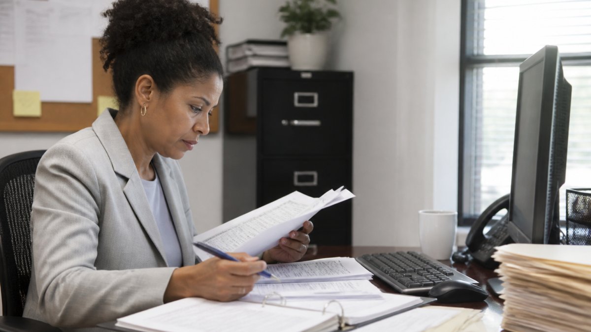 HR manager reviewing compliance documents and pre-adverse action notice templates at a desk with organized files and a computer showing FCRA compliance procedures